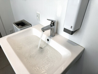 Water flowing from the faucet in the bathroom. Clogged sink