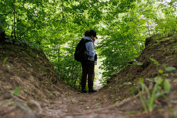 Mother holding baby looking up into forest. Nature walk with baby, peaceful moment outdoors, family bonding in forest.