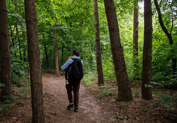 Mother carrying baby in her arms while walking in the forest. View from the back. Walking in nature with baby, peaceful moment in the fresh air, family bonding in the forest.