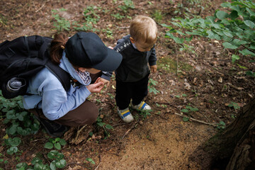 Mother teaching baby about nature in forest. Family time and early childhood education in nature.