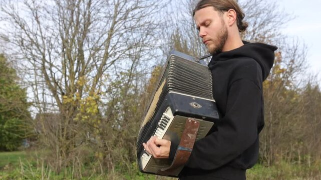 a man plays the accordion in an autumn garden