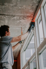 A worker measures a window frame with a laser ruler.