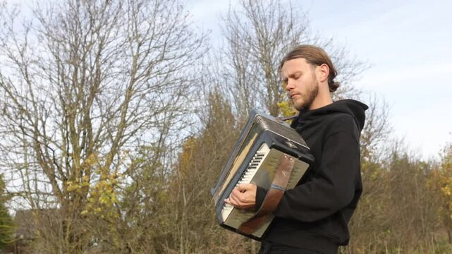 a man plays the accordion in an autumn garden