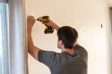 A man is currently using a powerful drill to create a hole in a wall