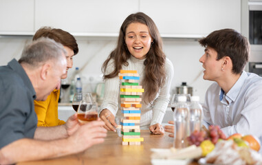 Happy young girl concentrating on removing block from tower while playing , spending free time with...