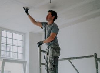 One worker inspects the ceiling with his finger.