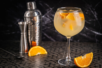 A glass of orange cocktail with ice cubes on dark background. Summer refreshing cocktail screwdriver or agua de Valencia or white sangria . High quality photo