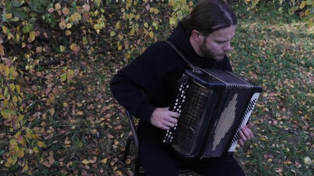 a man plays the accordion in an autumn garden