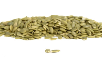 Selective focus on two peeled pumpkin seeds on white background. Focus on foreground, background is blurred.