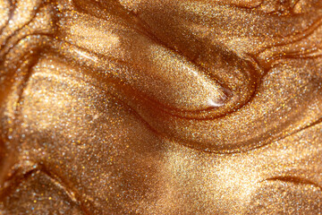 Texture background with golden shimmering cosmetic body spray or gel. Glowing backdrop.