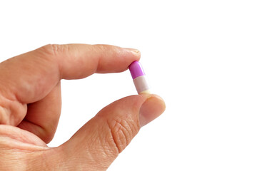 Hand holding a purple and white capsule