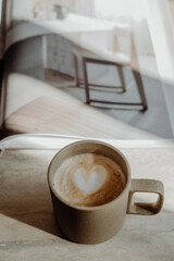 Minimalistische Kaffeepause mit einer Tasse Cappuccino auf einem Magazin – ästhetische Lifestyle-Szene mit Fokus auf Ruhe, Stil und skandinavischem Flair