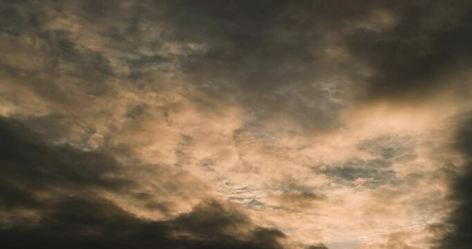 Timelapse of the sky with multiple layers of clouds first romantically tinted by the light of setting sun and then gradually getting darker and more dramatic and denser