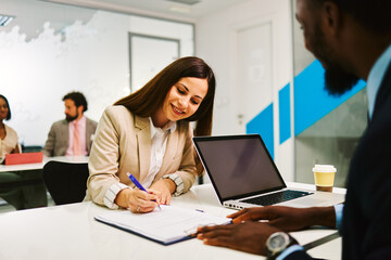 Businesswoman signing contract with her advisor using laptop in the office