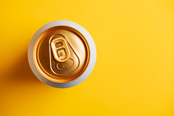 Top-down view of a golden drink can on a vibrant yellow background. Top view