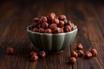 Hazelnuts in a bowl on a dark wooden background. Front view