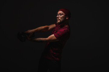Stylish male photographer in red beanie and graphic tee posing in dramatic low key lighting,...