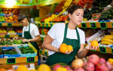 Portrait of cheerful woman marketer working at fruit department of store