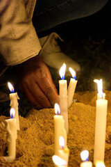 Hand placing a candle as an offering during prayers at a religious festival