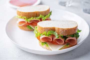 Sandwich with ham, cheese and lettuce on a white background