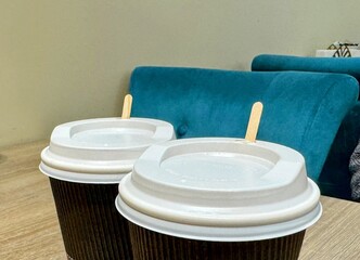Two disposable coffee cups with lids and stirrers