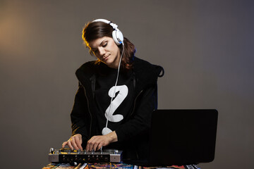 Female DJ on a mixer. Girl playing texhno music against gray background.