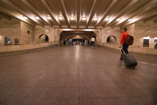 A man in red jumper pulling from his suitcase entering the train station