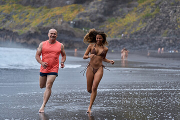 Smiling couple running on beach