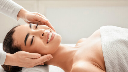 Smiling korean woman in spa salon enjoying relaxing head massage, young asian lady lying on table with closed eyes, pampering herself with professional beauty treatments and procedures, closeup