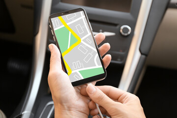 Woman connecting charging cable to mobile phone with city map on screen in car, closeup