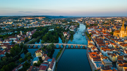Regensburg at sunset captured from above, featuring the iconic Stone Bridge over the Danube River...