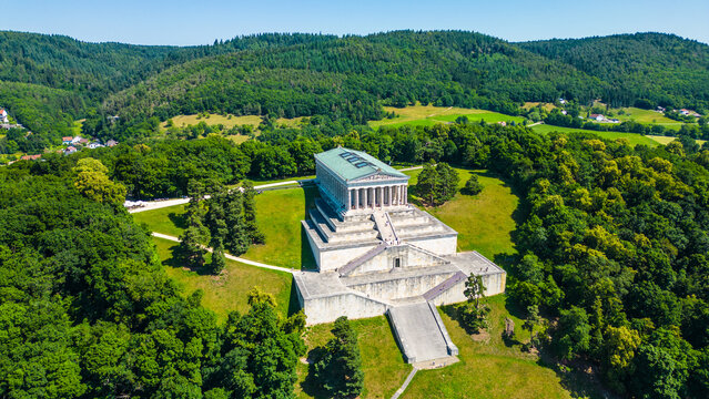 Walhalla memorial near Regensburg captured from a drone on a sunny day, perched above the Danube River with classical architecture and panoramic views of the Bavarian countryside