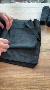 A woman rolls black microfiber cloths into tubes. She arranges them in a row. Reviewing her purchase. Vertical video