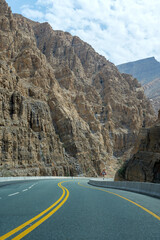 Lonely road winding through rugged mountain landscape. Mountain road, drive, route - ideal for travel, adventure, and driving freedom