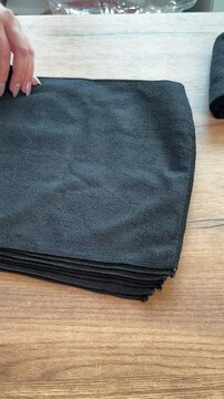 A woman rolls black microfiber cloths into tubes. She arranges them in a row. Reviewing her purchase. Vertical video.