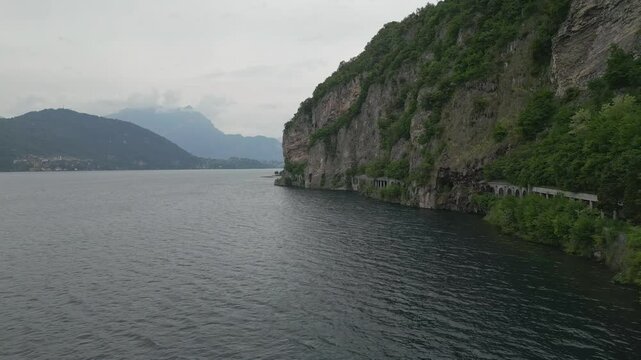 Mountain road tunnels along Lake Como between Olcio and Lierna, Italy, with lush cliffs and scenic alpine backdrop on a summer day