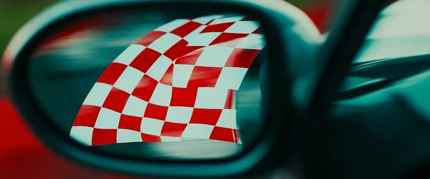 A checkered flag is reflected in a car's rearview mirror. The flag is red and white, and it is waving in the wind. Concept of motion and excitement