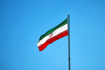 Flag of Iran. Flag of the Islamic Republic of Iran in front of a clear blue sky. Iranian flag...