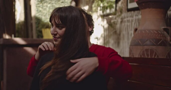 Couple in love, spending time together. Man gives his girlfriend a shoulder massage, she smiles and enjoys the moment.