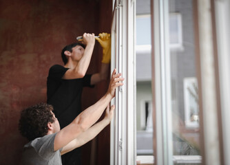 Young people install a window frame.