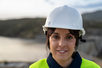Female engineer smiling and wearing hardhat at worksite