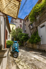 A blue city scooter is left in front of the entrance to a tenement house in the old town in Croatia...