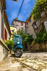 A blue city scooter is left in front of the entrance to a tenement house in the old town in Croatia...