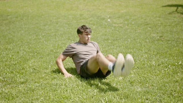 Young athletic man doing v-ups in a park during the day.