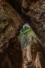 Hidden among high rocks narrow entrance to hidden beach in Vrbnik on KRK island, Croatia,