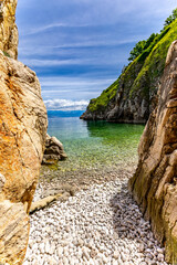 The crystal clear blue water of the Adriatic Sea, a hidden entrance to a small beach that is a...