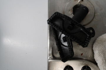 High-angle view of cleaning brush attachment for steam cleaner removing burned food from stove top,...