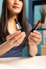 Selective focus on various lipstick shades held by a beautiful woman, showcasing them to the camera...