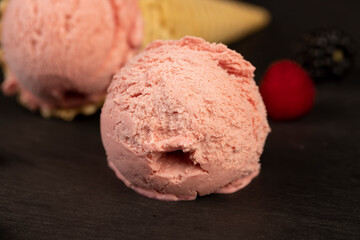 melting ice cream on a black slate board, sweet cold pink ice cream with strawberry flavor, ice cream in a waffle cone