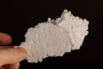 white foam for transporting or building insulation close up, white foam made from a large number of spherical pieces joined together, hold the material in your hands